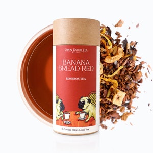 May include: A brown cardboard tube with a red label that says "OPEN DOOR TEA BANANA BREAD RED ROOIBOS TEA". The label also features a cartoon illustration of two pugs sitting at a table with cups of tea. The tube contains 3 ounces (85g) of loose leaf tea.
