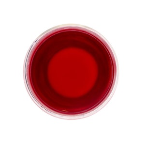 May include: A clear glass cup filled with a bright red liquid, likely tea or juice.