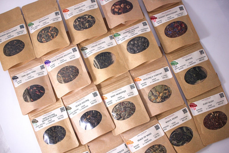 May include: Assortment of 18 small brown paper bags filled with loose leaf tea. Each bag has a label with the name of the tea blend, brewing instructions, and a QR code.