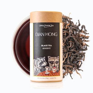 May include: A brown cardboard tube with a black label that says "OPEN DOOR TEA" and "DIAN HONG BLACK TEA RESERVE". The label also features two raccoons drinking tea. The tube contains 1.25 ounces (35g) of loose leaf tea.