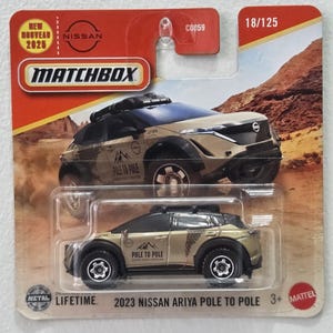 May include: A Matchbox toy car of a 2023 Nissan Ariya Pole to Pole. The die-cast car is tan and black with the text "POLE TO POLE" on the side. The packaging includes the Matchbox logo, Nissan branding, and the number 18/125.