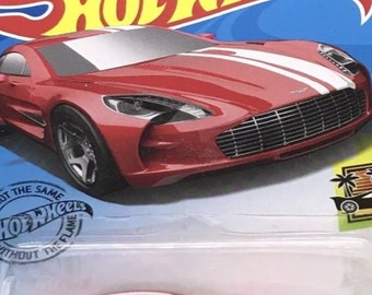 May include: Red die-cast toy car with white racing stripes. The car is a Hot Wheels model and is part of the Hot Wheels collection.