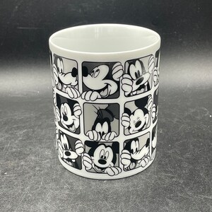 Pu&ograve; includere: Tazza in ceramica bianca con un design in bianco e nero dei volti di Topolino e Paperino in un motivo a griglia.