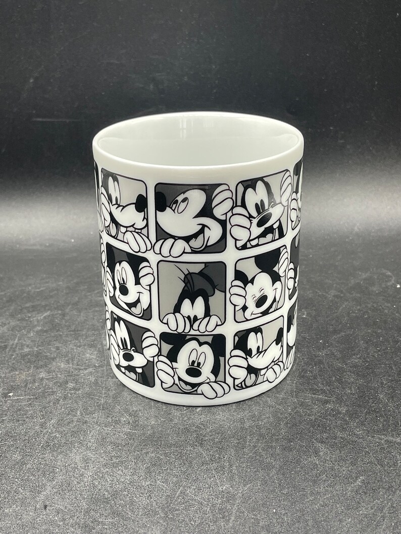 Pu&ograve; includere: Tazza in ceramica bianca con un design in bianco e nero dei volti di Topolino e Paperino in un motivo a griglia.