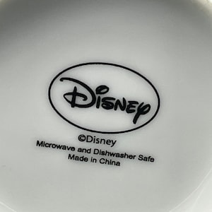 Pu&ograve; includere: Tazza in ceramica bianca con logo Disney nero e il testo "&copy;Disney Adatto per microonde e lavastoviglie Prodotto in Cina".