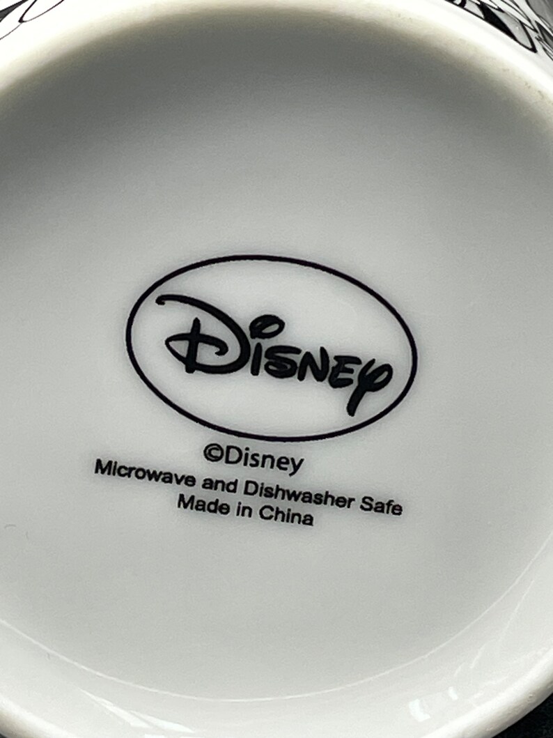 Pu&ograve; includere: Tazza in ceramica bianca con logo Disney nero e il testo "&copy;Disney Adatto per microonde e lavastoviglie Prodotto in Cina".