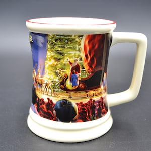 May include: A ceramic Christmas mug with a festive scene featuring Santa Claus in a sleigh, reindeer, and a Christmas tree. The mug has a white base, handle, and rim with a red accent.