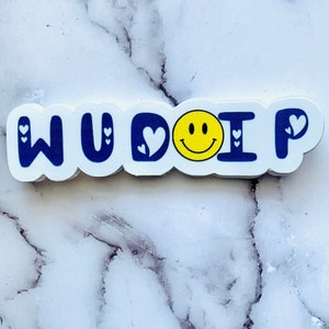 May include: White sticker with the text "WU DO I P" in blue letters with white hearts around each letter. A yellow smiley face is in the center of the sticker.