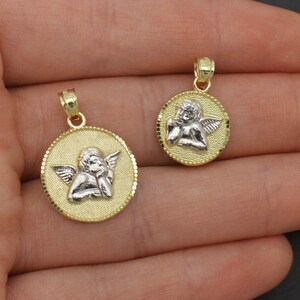 May include: Two gold angel pendant necklaces with a white angel design. The larger pendant is about 1 inch in diameter and the smaller pendant is about 3/4 inch in diameter.