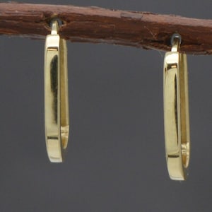 May include: A pair of gold hoop earrings. The earrings are simple and elegant, with a smooth, polished finish.