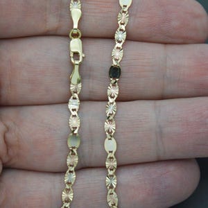 May include: A gold chain necklace with a diamond-cut design. The chain is made of three different colours of gold: yellow, white, and rose.