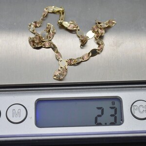 May include: A gold chain necklace with a textured design. The chain is on a digital scale that reads 2.3 grams.