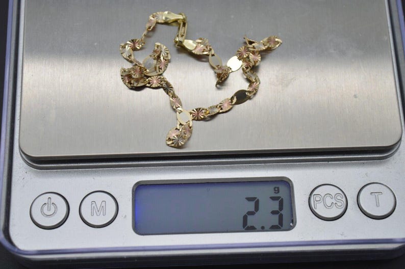 May include: A gold chain necklace with a textured design. The chain is on a digital scale that reads 2.3 grams.