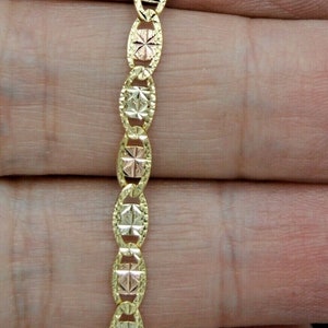 Puede incluir: Un collar de cadena de oro con un diseño de eslabón ovalado texturizado. La cadena está hecha de tres colores de oro diferentes: amarillo, blanco y rosa.