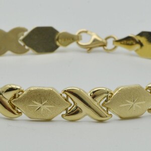 May include: A gold bracelet with a diamond-shaped link pattern. The links are textured and have a starburst design.
