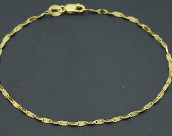 May include: A gold chain bracelet with a delicate, flat, oval-shaped link design.