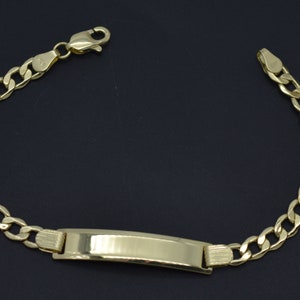 May include: A gold chain bracelet with a rectangular ID tag. The chain is a curb style and the tag is smooth and shiny.