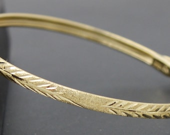 Puede incluir: Un brazalete de oro con un delicado diseño grabado. El brazalete es simple y elegante.