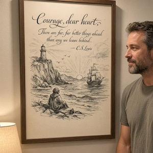 May include: A framed wall art print featuring a black and white ink illustration of a lighthouse, a sailing ship, and a person sitting on a rocky shore. The text reads: Courage, dear heart, There are far, far better things ahead than any we leave behind. -C.S.Lewis