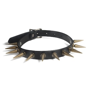 May include: Black leather choker with gold-toned spikes. The choker has a buckle closure.