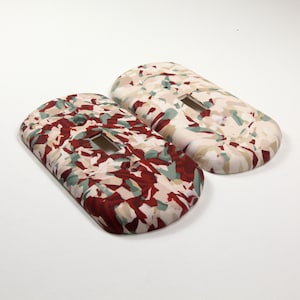 May include: Two decorative light switch covers with a camouflage pattern in shades of red, green, and white.