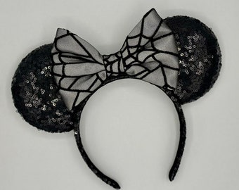 May include: Black sequined Minnie Mouse ears with a black and white spiderweb bow.