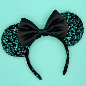 May include: Black headband with a large black bow and teal sequin mouse ears.