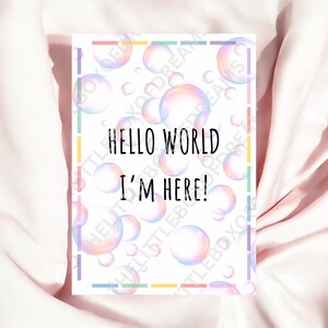 Puede incluir: Una tarjeta blanca con un borde de arcoíris y un fondo de burbujas iridiscentes. La tarjeta dice "Hello World I'm Here!"