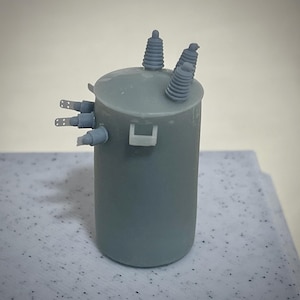 May include: A gray model of a small electrical transformer with three insulators on top.