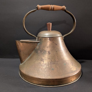May include: A vintage copper kettle with a wooden handle and lid. The kettle has a tarnished finish and a flared base.