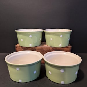 May include: Four green ceramic ramekins with white polka dots. The ramekins are arranged in two rows of two.