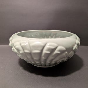 May include: A white ceramic bowl with a scalloped design. The bowl is glazed and has a smooth, glossy finish.