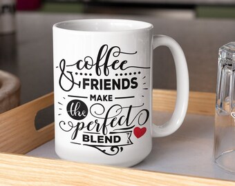 May include: White ceramic coffee mug with black text that reads "& coffee... FRIENDS make the perfect BLEND" with a red heart. The mug is on a wooden tray with a glass next to it.