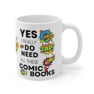 May include: White ceramic mug with a black and white comic book themed design. The text on the mug reads "YES I REALLY DO NEED ALL THESE COMIC BOOKS". The design includes colorful comic book speech bubbles with the words "SPECIAL EDITION", "ZAP!" and "OMG!"