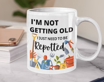May include: White ceramic mug with a black and white graphic of gardening tools and the text "I'm not getting old I just need to be repotted".
