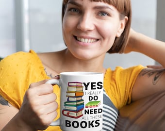 May include: White ceramic mug with a black and colorful graphic of a stack of books. The text on the mug reads "Yes I really do need all these books".