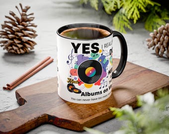 May include: A white coffee mug with a black handle and rim, filled with coffee. The mug features a vinyl record design with the words "YES I REALLY DO" and "Albums on Vinyl". Colorful musical notes and records decorate the mug.