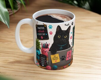 Op de afbeelding: Een witte keramische mok met een afbeelding van een zwarte kat die aan een laptop werkt. Het ontwerp bevat de teksten Pawsitive attitude every day, Coffee fuels great days, Top employee (fur real) en Treat breaks are important met pootafdrukken.