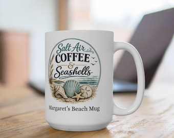 May include: White ceramic mug with a beach-themed design. The mug features the text "Salt Air Coffee & Seashells" in a circular design, along with illustrations of seashells and a starfish. The text "Margaret's Beach Mug" is printed below the design.