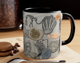 May include: A black and white ceramic coffee mug with a black handle. The mug features a pattern of various fossils, including a trilobite, ammonite, and a dinosaur bone.