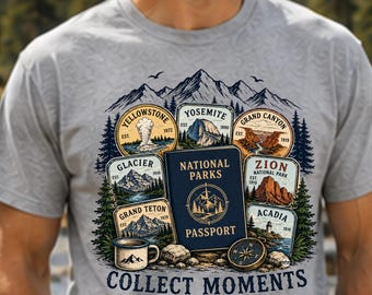 Op de afbeelding: Een grijs gemêleerd t-shirt met een afbeelding van een blauw National Parks paspoort omringd door illustraties van de parken Yellowstone, Yosemite, Grand Canyon, Glacier, Zion, Grand Teton en Acadia, met de tekst Collect Moments Not Things.