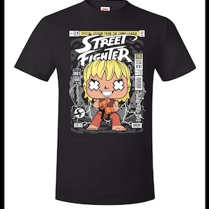 Puede incluir: Camiseta negra con un gráfico de estilo cómic de un personaje de Street Fighter. El diseño incluye el texto "Street Fighter" y "Special Edition From The Comic League". El personaje está en posición de combate.