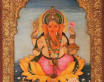 May include: A colorful painting of the Hindu deity Ganesha, depicted with an elephant head, four arms, and a large belly. He is seated on a lotus flower and holding a variety of objects, including an axe, a sweet, and a lotus flower. The painting is framed in a gold-colored frame with intricate designs.