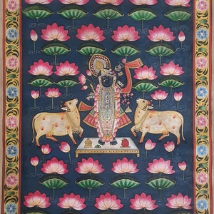 K&ouml;nnte beinhalten: Ein traditionelles indisches Gem&auml;lde, das eine hinduistische Gottheit zeigt, die auf einer Plattform steht, umgeben von Lotusblumen. Die Gottheit ist mit aufwendigen Schmuck und Kleidung geschm&uuml;ckt und h&auml;lt in einer Hand eine Waffe. Zwei K&uuml;he flankieren die Gottheit, und der Hintergrund ist dunkelblau.