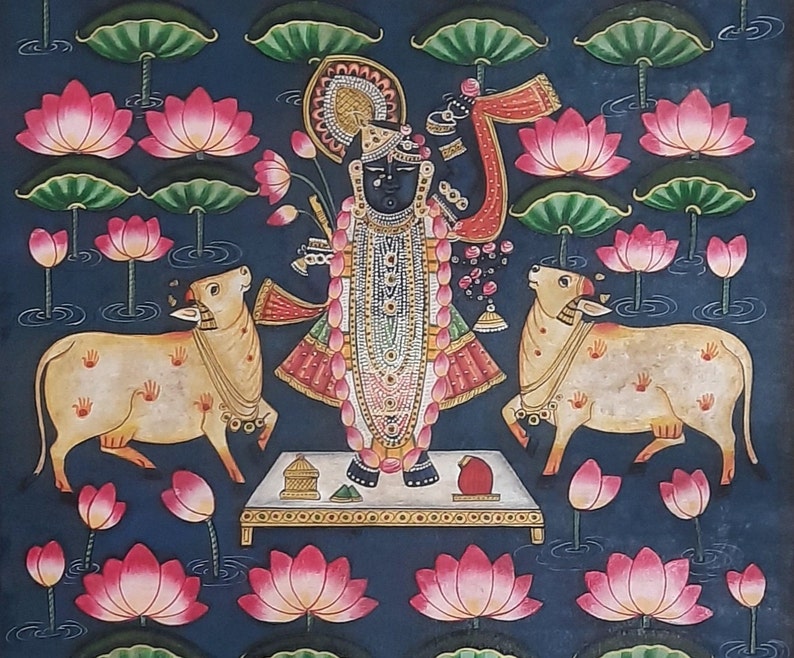 K&ouml;nnte beinhalten: Ein Gem&auml;lde, das eine hinduistische Gottheit, Krishna, darstellt, der auf einer Plattform mit zwei K&uuml;hen steht. Krishna ist mit aufwendigen Schmuck und Kleidung geschm&uuml;ckt und h&auml;lt eine Fl&ouml;te. Der Hintergrund ist dunkelblau mit Lotusblumen und Bl&auml;ttern.