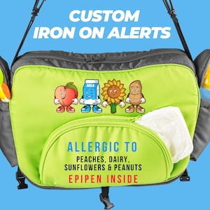 Puede incluir: Bolsa de pañales verde con un bolsillo con cremallera y una alerta personalizada de planchado que dice "Alérgico a melocotones, lácteos, girasoles y cacahuetes. Epipen dentro". La alerta presenta imágenes de dibujos animados de un melocotón, una caja de leche, un girasol y un cacahuete.