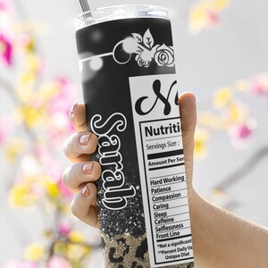 Puede incluir: Un vaso negro y dorado con un dise&ntilde;o de estampado de leopardo y el nombre "Sarah" en purpurina blanca. El vaso tiene una etiqueta nutricional con el texto "Nutriti" y "Servings Size: Amount Per Ser" y una lista de elementos que incluyen "Hard Working", "Patience", "Compassion", "Caring", "Sleep", "Caffeine", "Selflessness", "Front Line", "*Not a significant", "**Percent Daily Va", "Unique Diet".