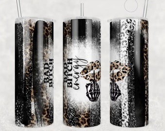 Può includere: Tre bicchieri in acciaio inossidabile con un design a stampa leopardata bianco e nero. I bicchieri hanno uno sfondo bianco con pennellate nere e il testo "Bad Bitch energy" in nero. I bicchieri hanno un coperchio nero e una cannuccia trasparente.