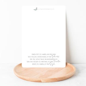 Peut inclure: Une carte blanche avec un motif de papillon gris en haut et une citation en allemand sur le fait d'avoir un foyer et une famille. La citation dit : "Einen Ort zu haben, an dem man sich fallen lassen kann, ist ein Zuhause. Ein Teil von etwas Wunderbarem zu sein und geliebt zu werden, ist eine Familie. Beides zu haben, ist ein Segen."