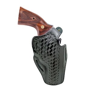 Pode incluir: Uma coldre de couro preto com um padr&atilde;o de tecido de cesta tran&ccedil;ada segura um rev&oacute;lver com uma empunhadura de madeira. A empunhadura do rev&oacute;lver &eacute; marrom escuro com um emblema dourado.